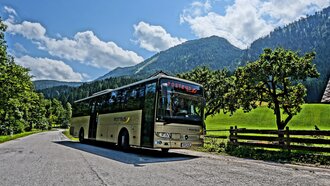 Ein Postbus hält an einer kurvenreichen Straße in den Bergen.