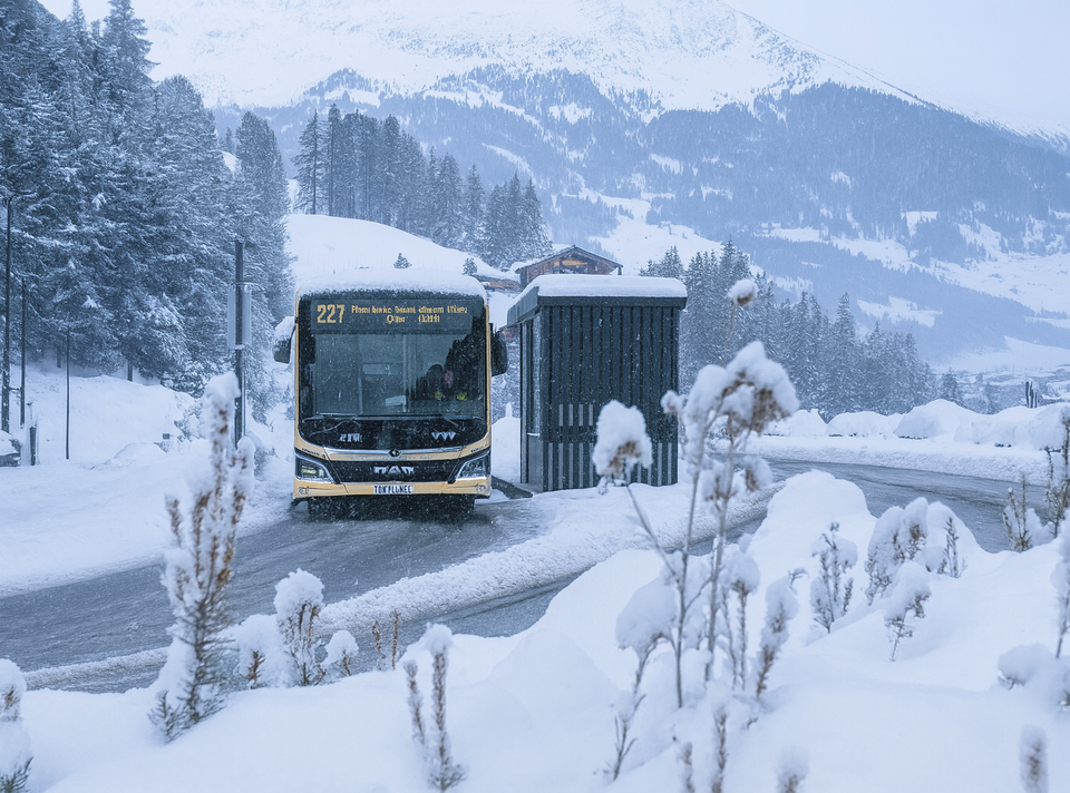 Bus stopt bij een halte in een besneeuwd landschap.