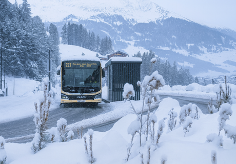 Bus stops at a shelter in a snowy landscape.