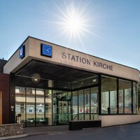 Modern subway station with glass front and clock in the Alps.