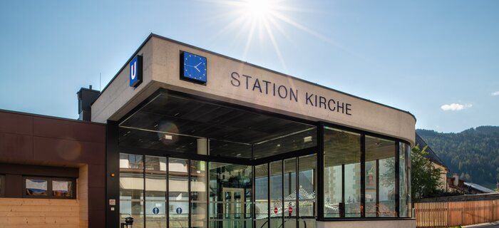 Moderne U-Bahn Station mit Glasfront und Uhr in den Alpen.