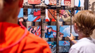 Children interacting with a game wall full of illustrations.