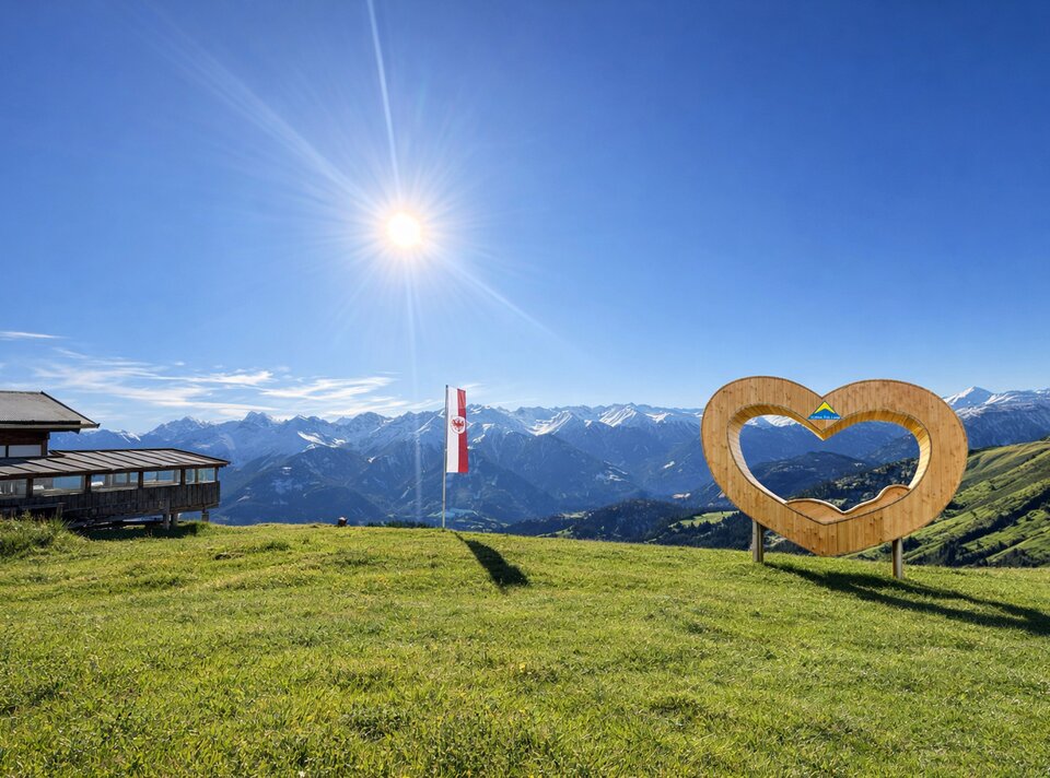 A heart-shaped structure with an alpine landscape under a blue sky.