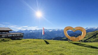 A heart-shaped structure with an alpine landscape under a blue sky.