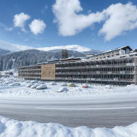 Ein modernes Hotel im Schnee mit Bergen im Hintergrund.