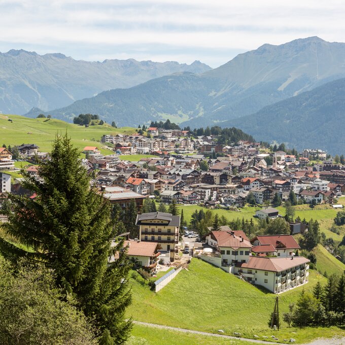 The image depicts a picturesque alpine town surrounded by mountains.