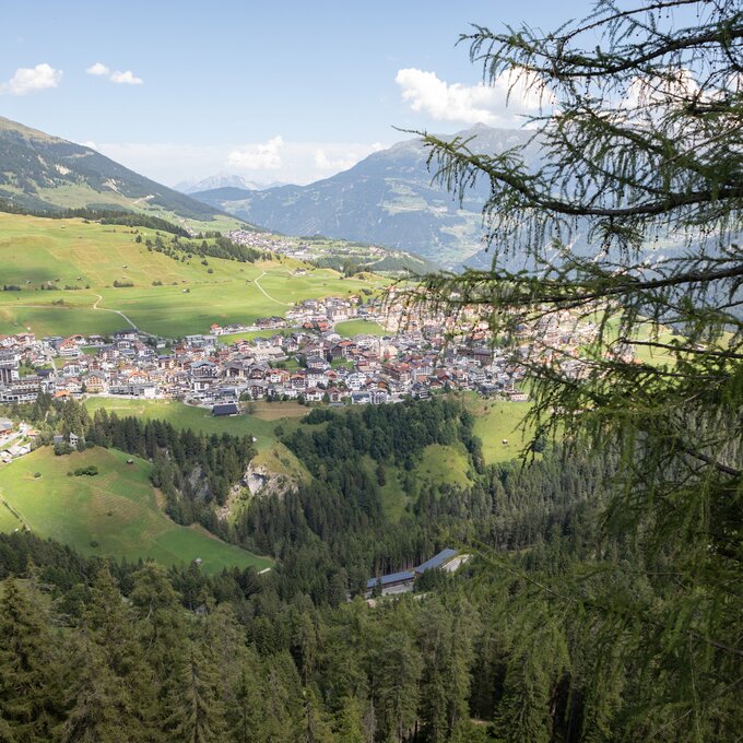 Aerial view of a picturesque mountain village surrounded by green meadows and mountains.