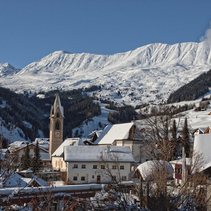 Schneebedeckte Berge umgeben ein charmantes Dorf im Winter.