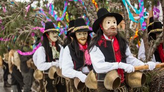 Menschen in Masken und traditionellen Kostümen bei einer Feier.