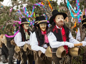 Menschen in Masken und traditionellen Kostümen bei einer Feier.