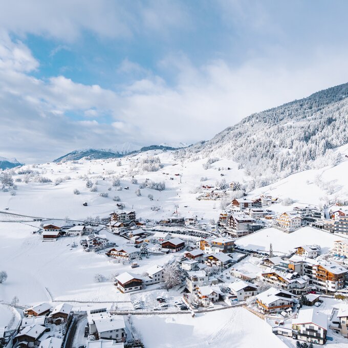 Winterlandschap met een sneeuwachtig dorp en bergen.