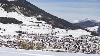 Panorama eines schneebedeckten Dorfes in den Alpen.