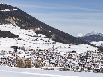 Panorama eines schneebedeckten Dorfes in den Alpen.