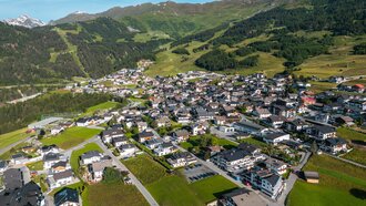 Blick auf ein malerisches Dorf in den Bergen mit grünen Wiesen.