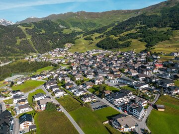 Blick auf ein malerisches Dorf in den Bergen mit grünen Wiesen.