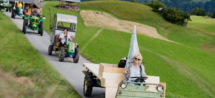 Eine Gruppe von Traktoren fährt auf einer Straße durch die Berge.