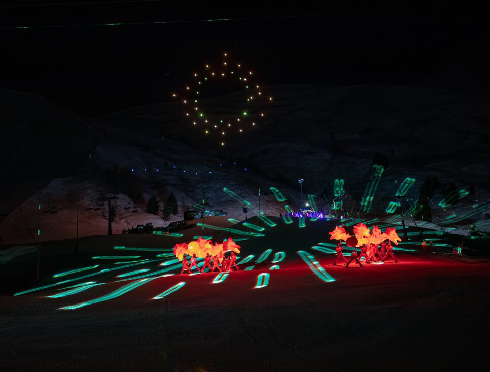 Bunte Lichtshow mit Pferden auf der Skipiste im Dunkeln.
