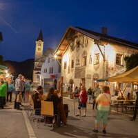 Lebhafte Marktansicht bei Nacht mit Menschen und Ständen.