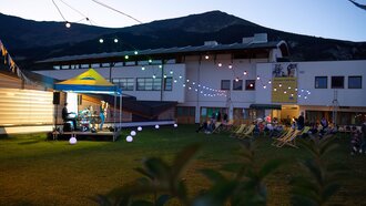Stage with musicians at dusk, audience seated outdoors.
