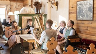 Vijf muzikanten spelen samen in een rustieke ruimte.
