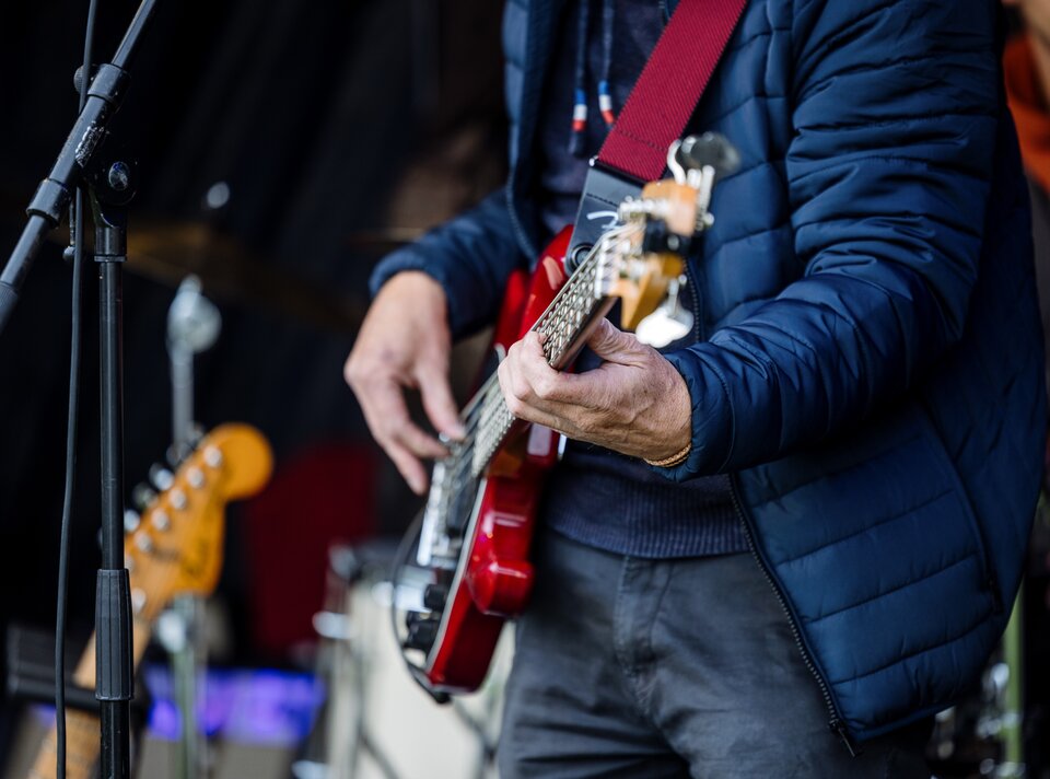 Ein Gitarrist spielt auf einer roten E-Gitarre auf einer Bühne.