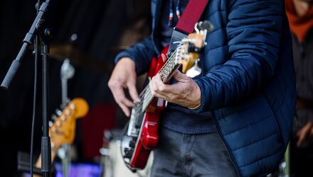 Ein Gitarrist spielt auf einer roten E-Gitarre auf einer Bühne.