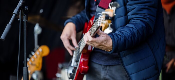 Ein Gitarrist spielt auf einer roten E-Gitarre auf einer Bühne.