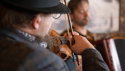 Ein Musiker spielt Geige, während ein anderer Akkordeon spielt.