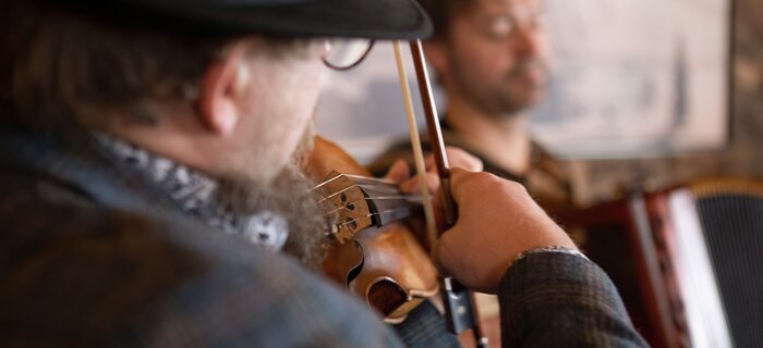 A musician plays the violin while another plays the accordion.