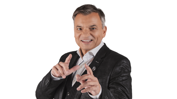 Ein lächelnder Mann posiert in einem eleganten Anzug mit einem freundlichen Ausdruck.