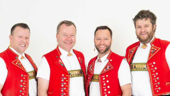 Vier Männer in roter Tracht posieren freundlich.