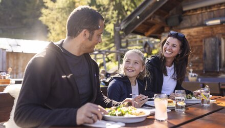 Eine Familie isst zusammen draußen und hat Spaß beim Essen.