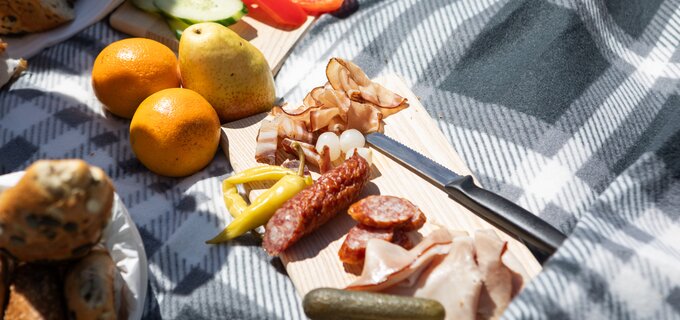 Brett mit Wurst, Käse und frischem Obst beim Picknick.
