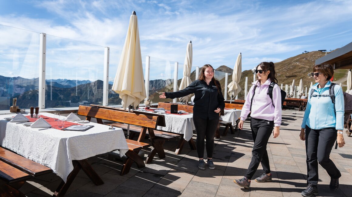 Drei Frauen spazieren in einem Restaurant mit Bergblick.