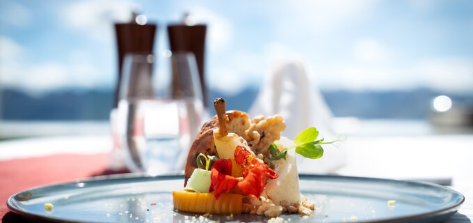 Ein kunstvoll angerichtetes Dessert mit Obst und essbaren Blüten, serviert in einer eleganten Umgebung.