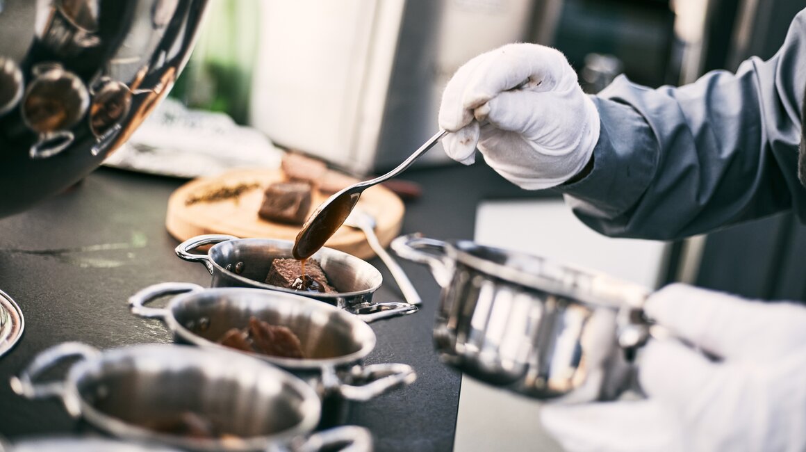 A chef serves sauces with a spoon.