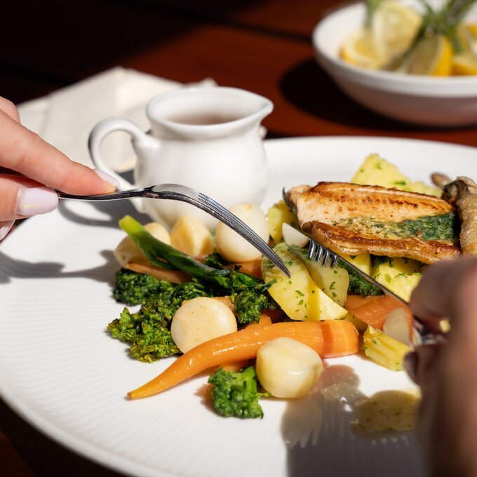 Detailaufnahme eines gefüllten Tellers mit Fisch und frischem Gemüse.