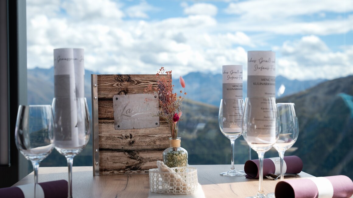 Eleganter Tisch mit Menükarten und Gläsern, Blick auf die Berge.