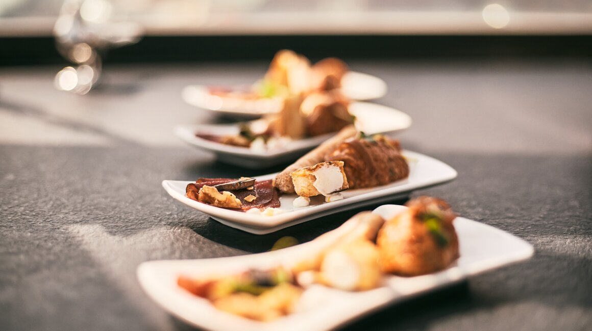 Various exquisite dishes on white plates, elegantly presented.