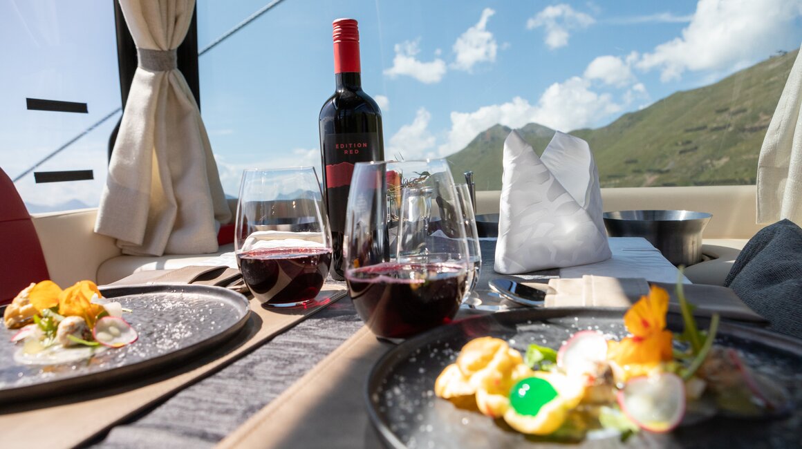 Ein luxuriös gedeckter Tisch mit Gourmetgerichten und Rotwein, umgeben von einer malerischen Landschaft.