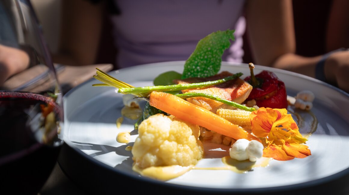 Ein kunstvolles Gemüsegericht mit Karotten, Blumenkohl und Wein.