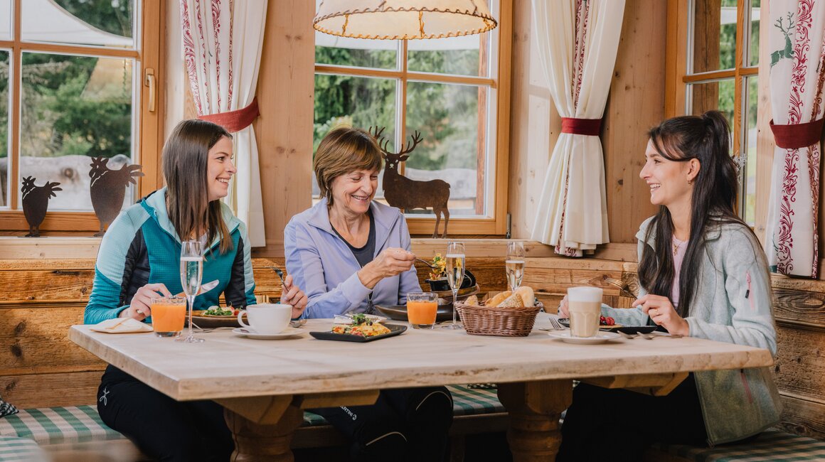Three women enjoying their meals in a rustic cabin.