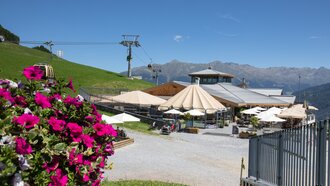 Sonniger Tag im Bergrestaurant mit Seilbahn und Blumen.