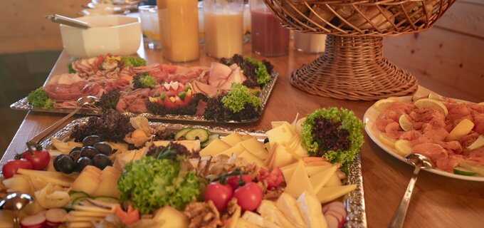 Ein reichhaltiges Frühstücksbuffet mit Wurst, Käse, Obst und Säften.