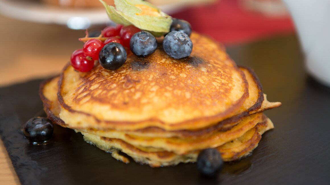Gestapelte Pancakes mit Heidelbeeren und roten Johannisbeeren.