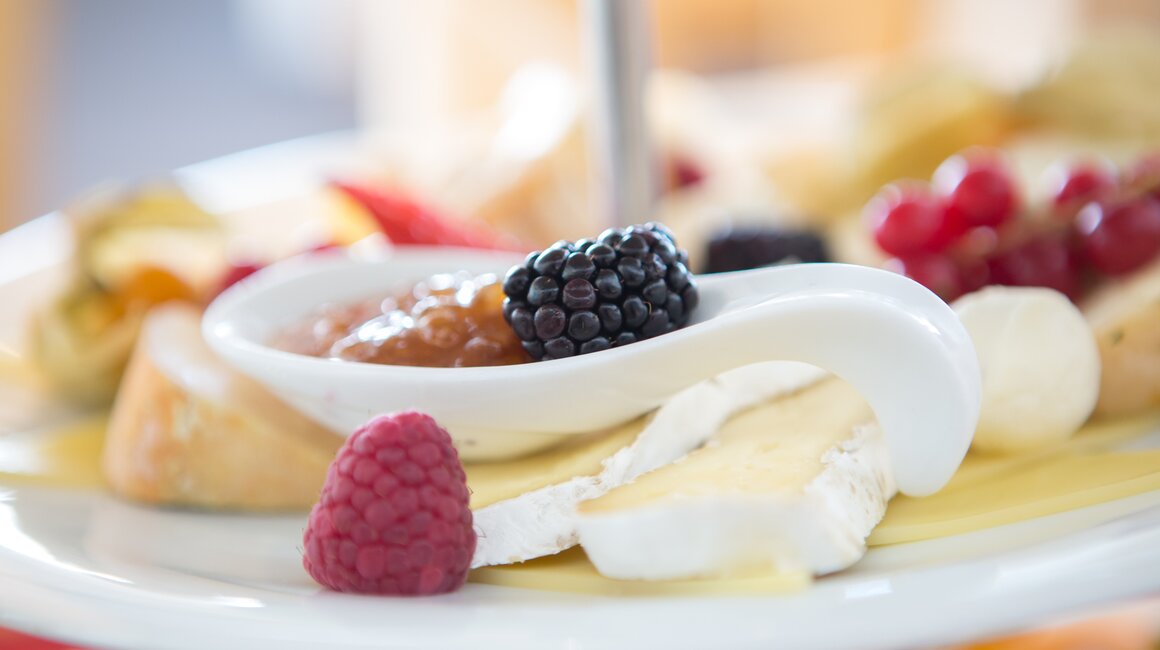 Käse mit Beeren und Marmelade auf einem dekorativen Teller.