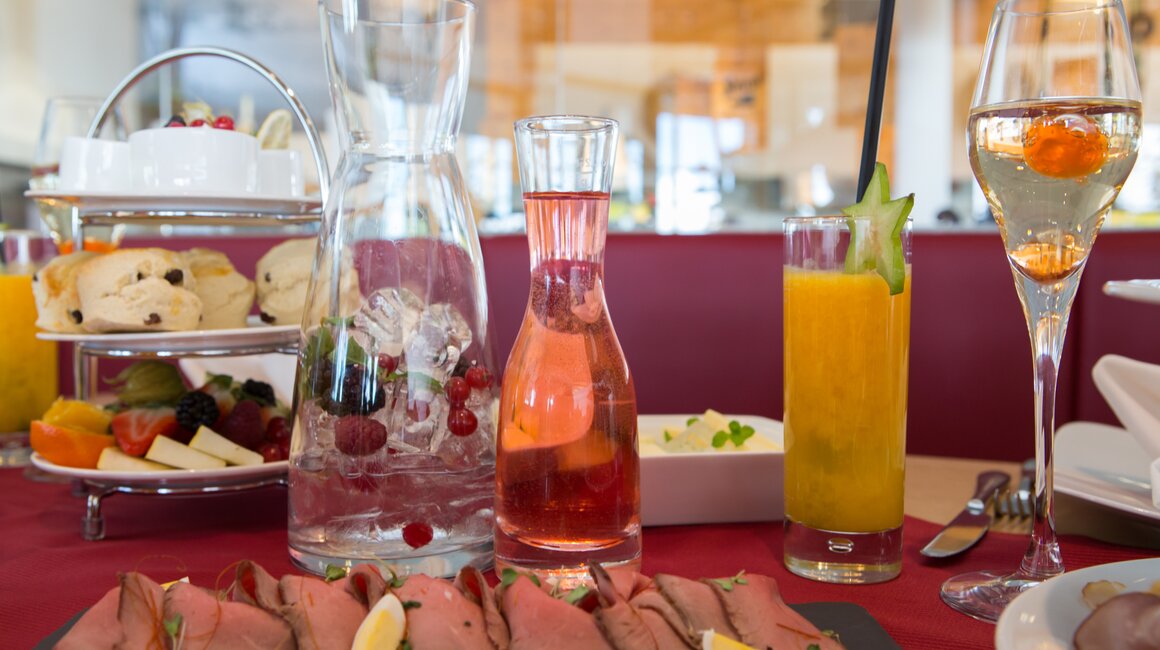 Ein gedeckter Tisch mit Rinderbraten, Getränken und Gebäck.