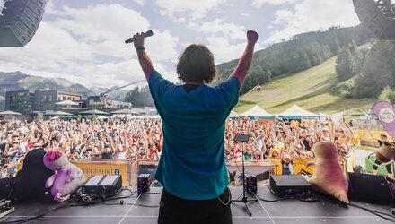 Ein Künstler mit Mikrofon steht auf der Bühne und begeistert das Publikum.