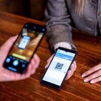 Eine Person scannt einen QR-Code auf einem Smartphone zur Bezahlung.