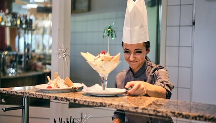 Eine Köchin serviert ein Dessert in einer eleganten Küche.